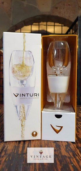 Un decantador de vino en una caja al lado de una copa de vino.