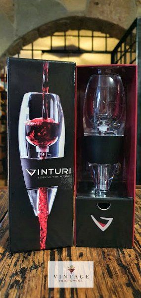 Un decantador de vino y una copa de vino están en una caja sobre una mesa de madera.