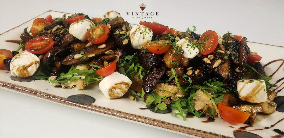 Una ensalada con tomates y queso en un plato blanco.