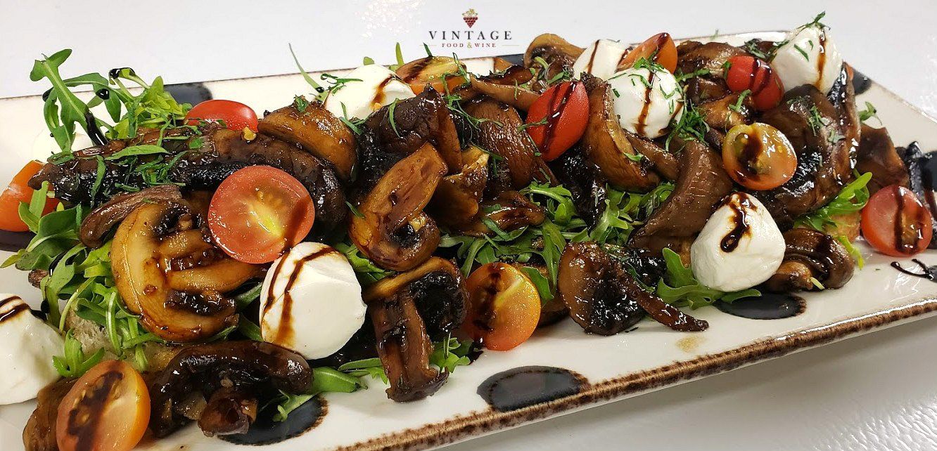 Un plato de comida con champiñones, tomates y queso sobre una mesa.