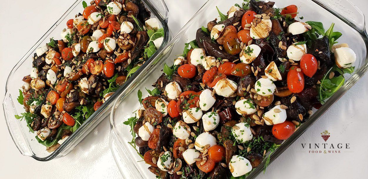 Sobre una mesa hay dos cazuelas llenas de verduras y queso.