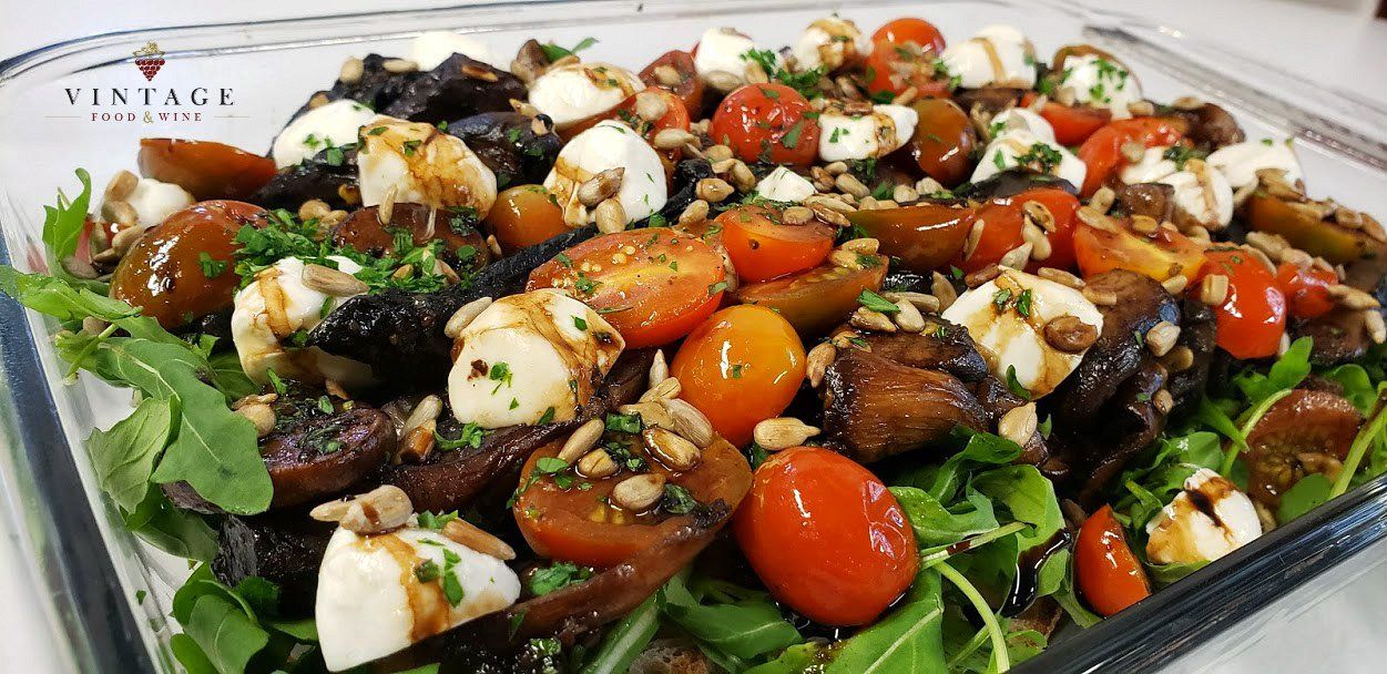 Un primer plano de una ensalada con tomates, mozzarella y nueces en un plato.