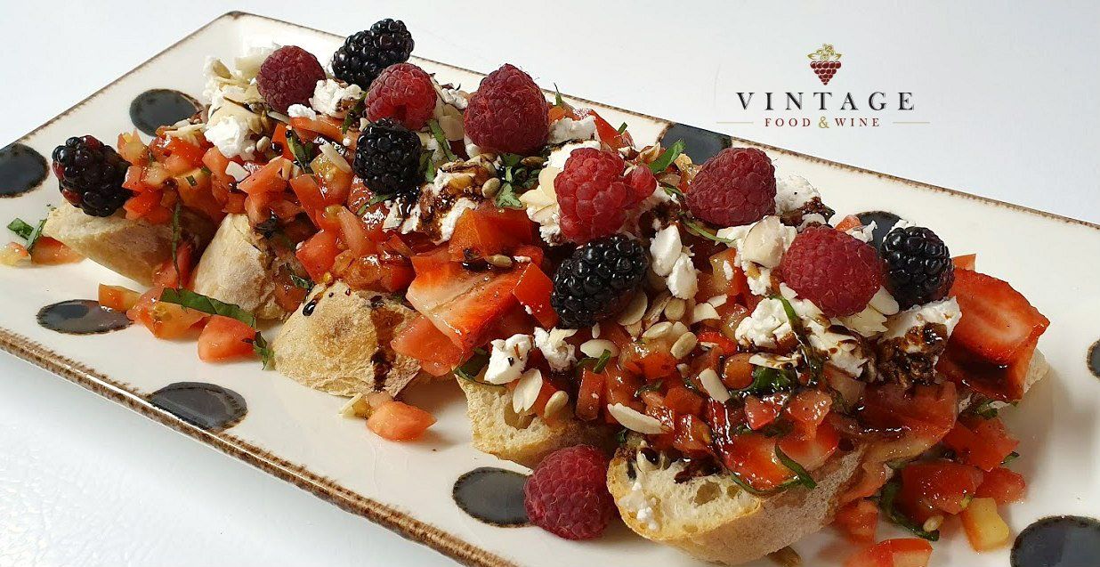 Un plato de comida con bayas y tomates encima.