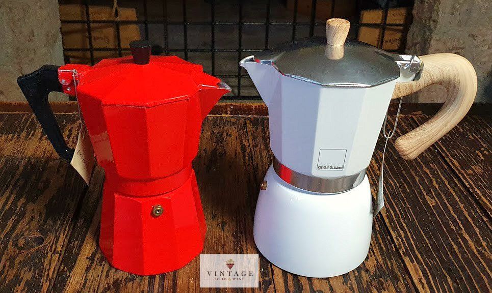 Dos cafeteras, una roja y otra blanca, están sobre una mesa de madera.