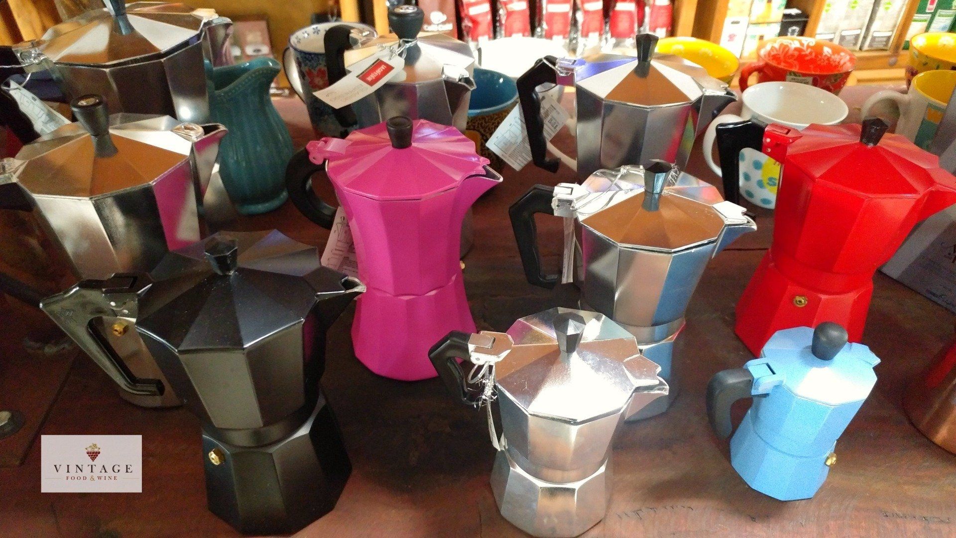 Un montón de cafeteras de diferentes colores sobre una mesa.