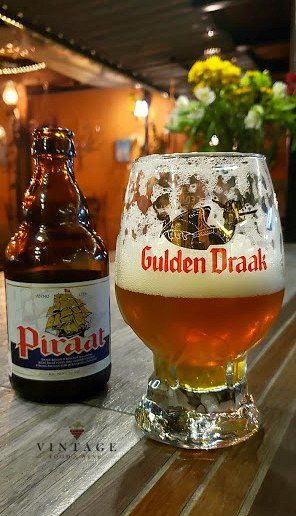 Una botella de gulden draak junto a un vaso de cerveza