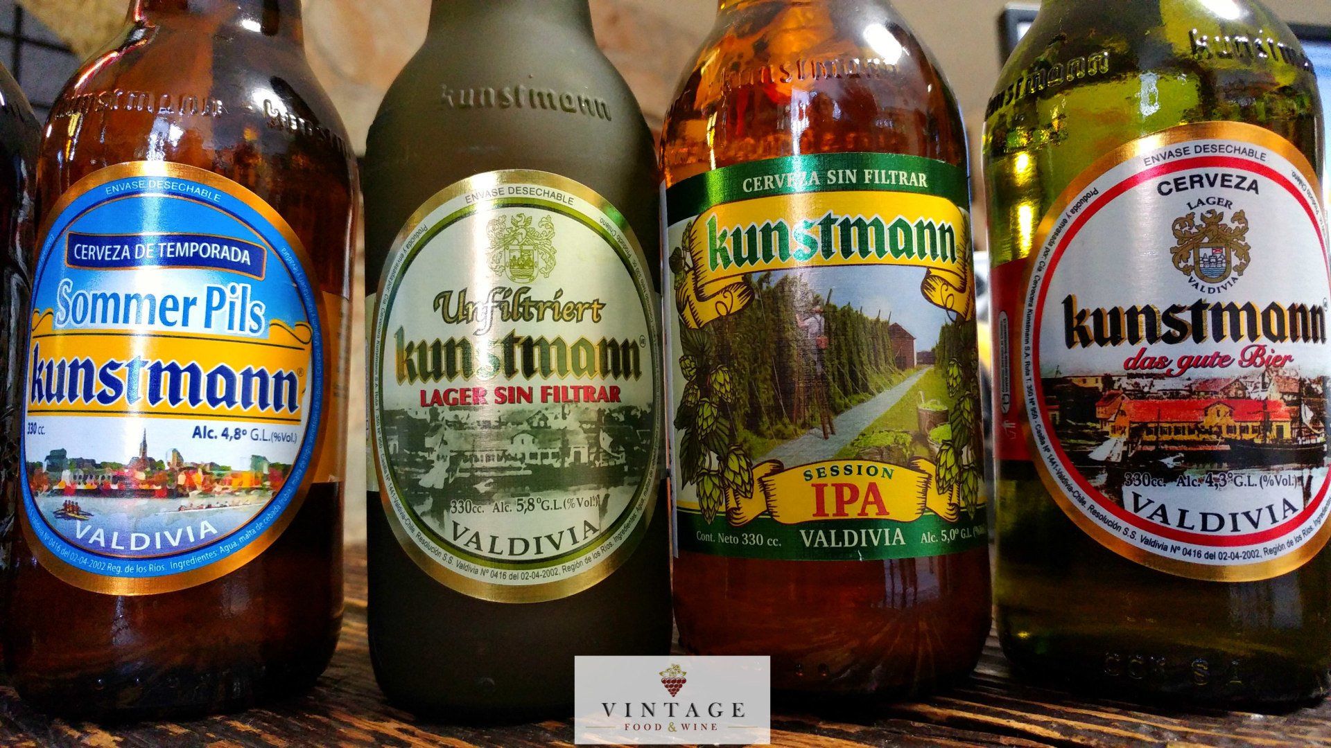 Cuatro botellas de cerveza Kunstmann están alineadas sobre una mesa.