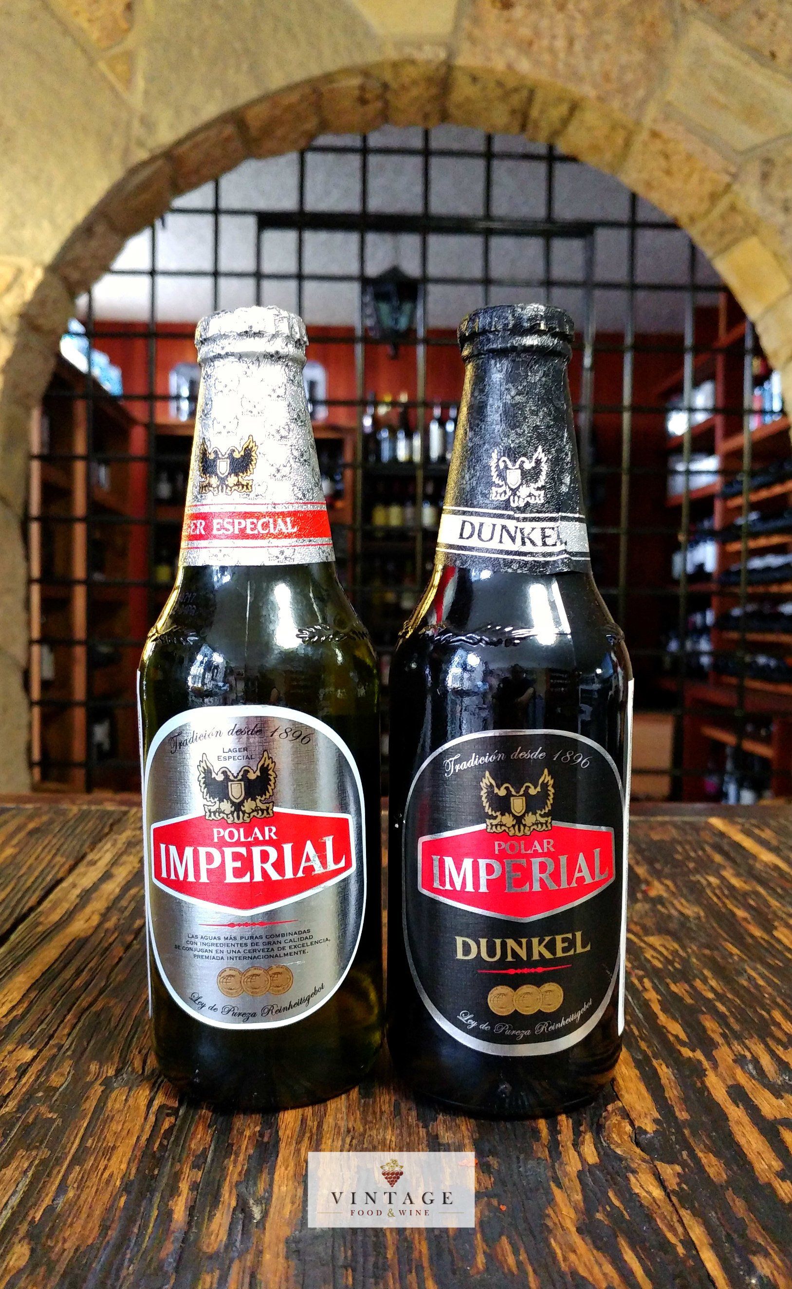 Dos botellas de cerveza imperial están sobre una mesa de madera.