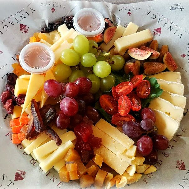 Un plato de queso, uvas y tomates sobre un papel que dice vintage.