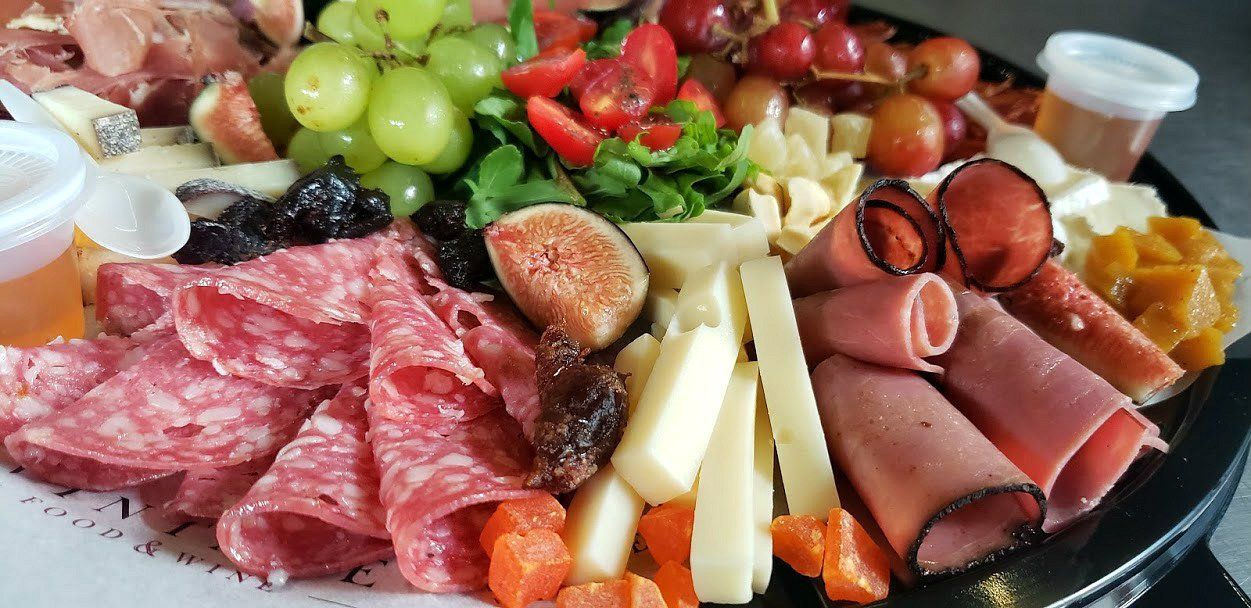 Un plato de comida con carne, queso, fruta y verduras sobre una mesa.
