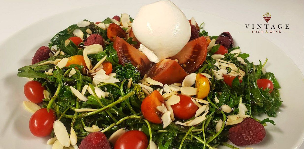 Una ensalada con tomates y frambuesas en un plato blanco.