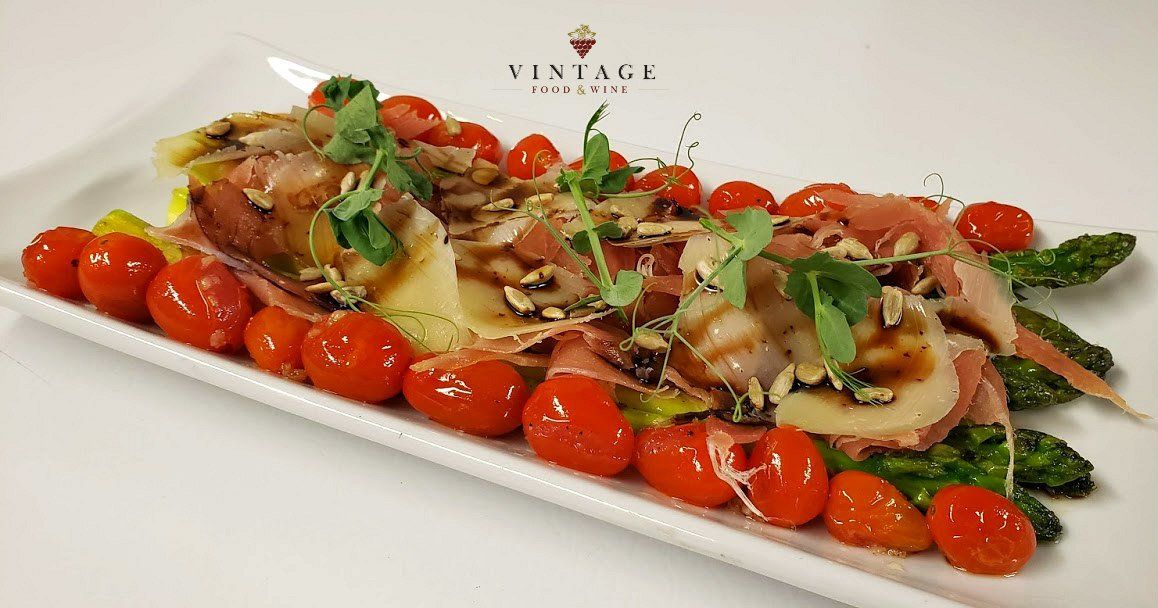 Un plato blanco cubierto con tomates, espárragos y carne.