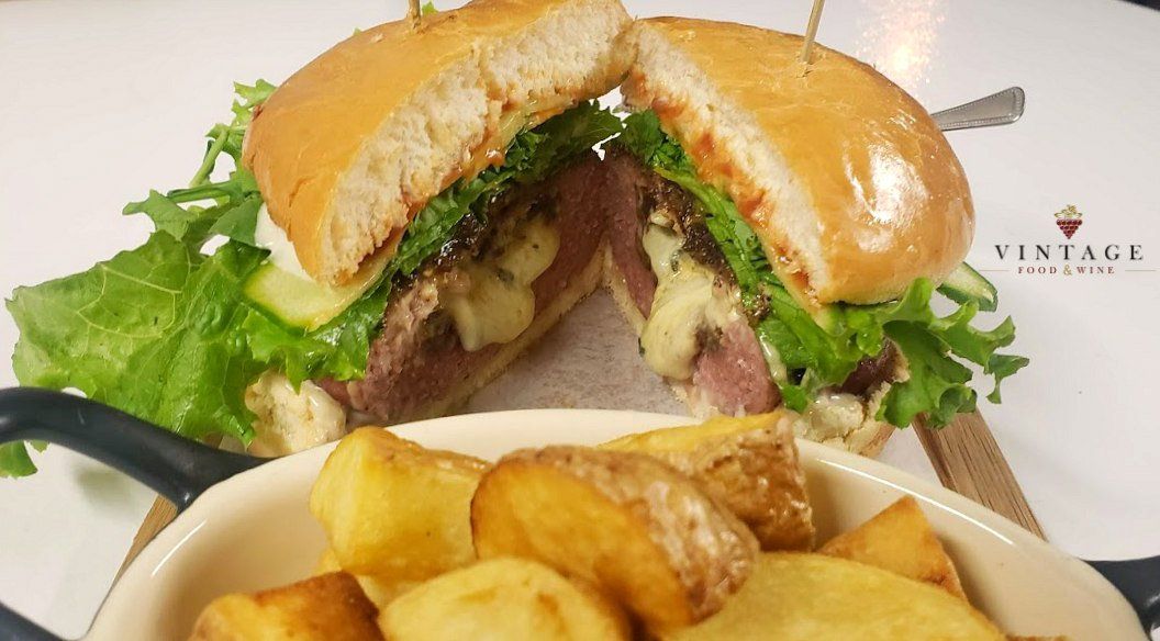 Un sándwich cortado por la mitad al lado de un bol de patatas.