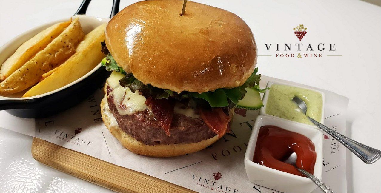 Una hamburguesa y papas fritas están en una tabla de cortar de madera.