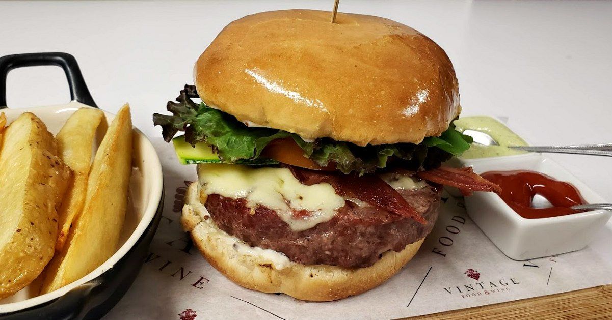 Una hamburguesa y patatas fritas están sobre una mesa.