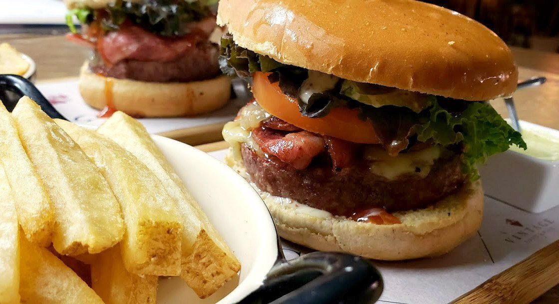 Un primer plano de una hamburguesa y papas fritas en una mesa.