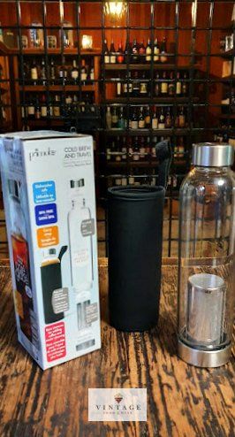 Una botella de agua de vidrio está sobre una mesa de madera al lado de una caja.