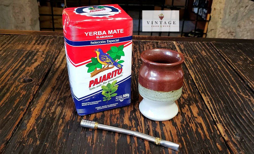 Una caja de yerba mate y una taza sobre una mesa de madera.
