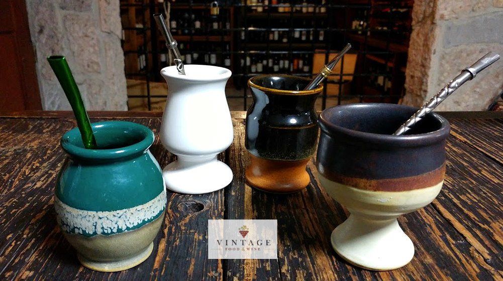 Un grupo de tazas de cerámica con pajitas están colocadas sobre una mesa de madera.