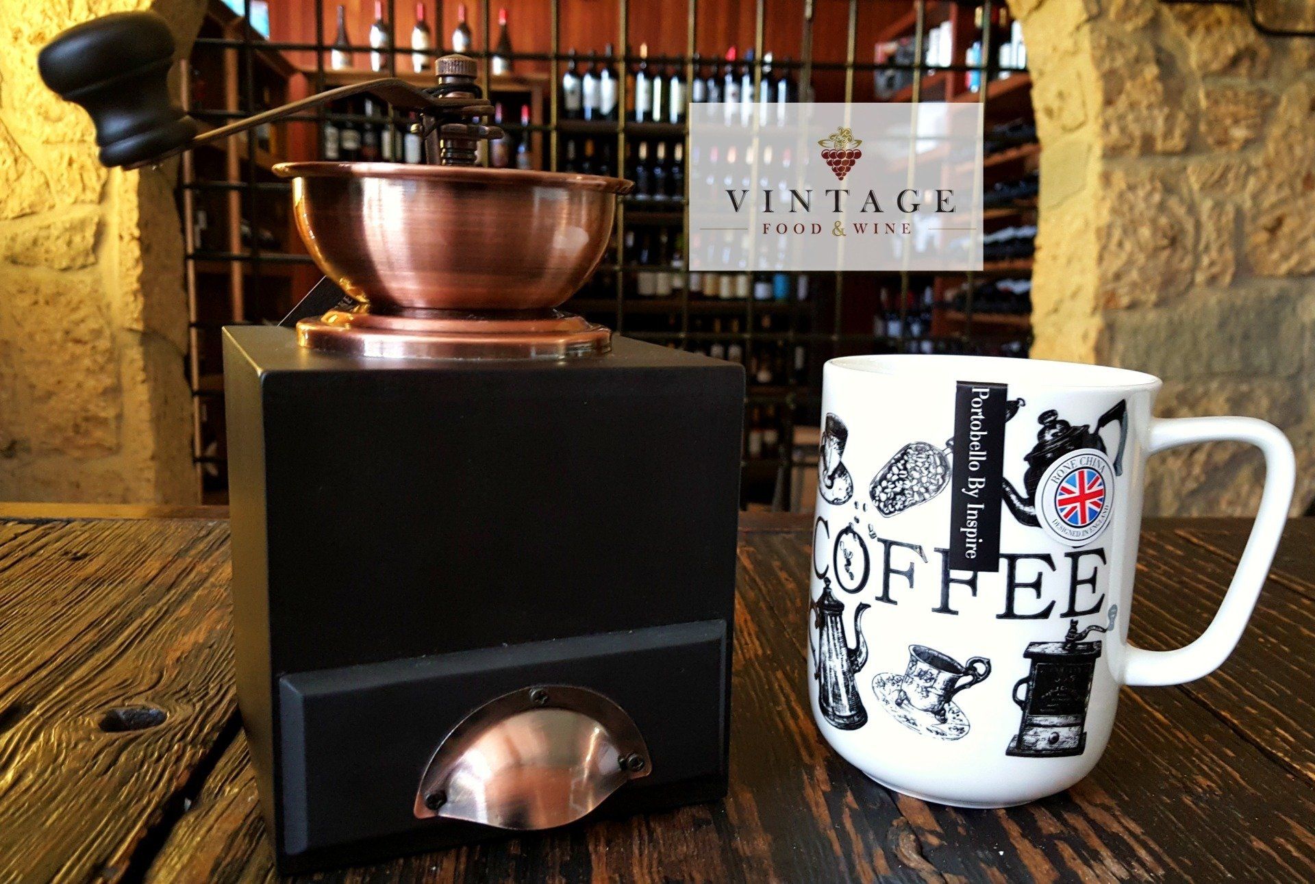 Un molinillo de café y una taza de café sobre una mesa de madera.