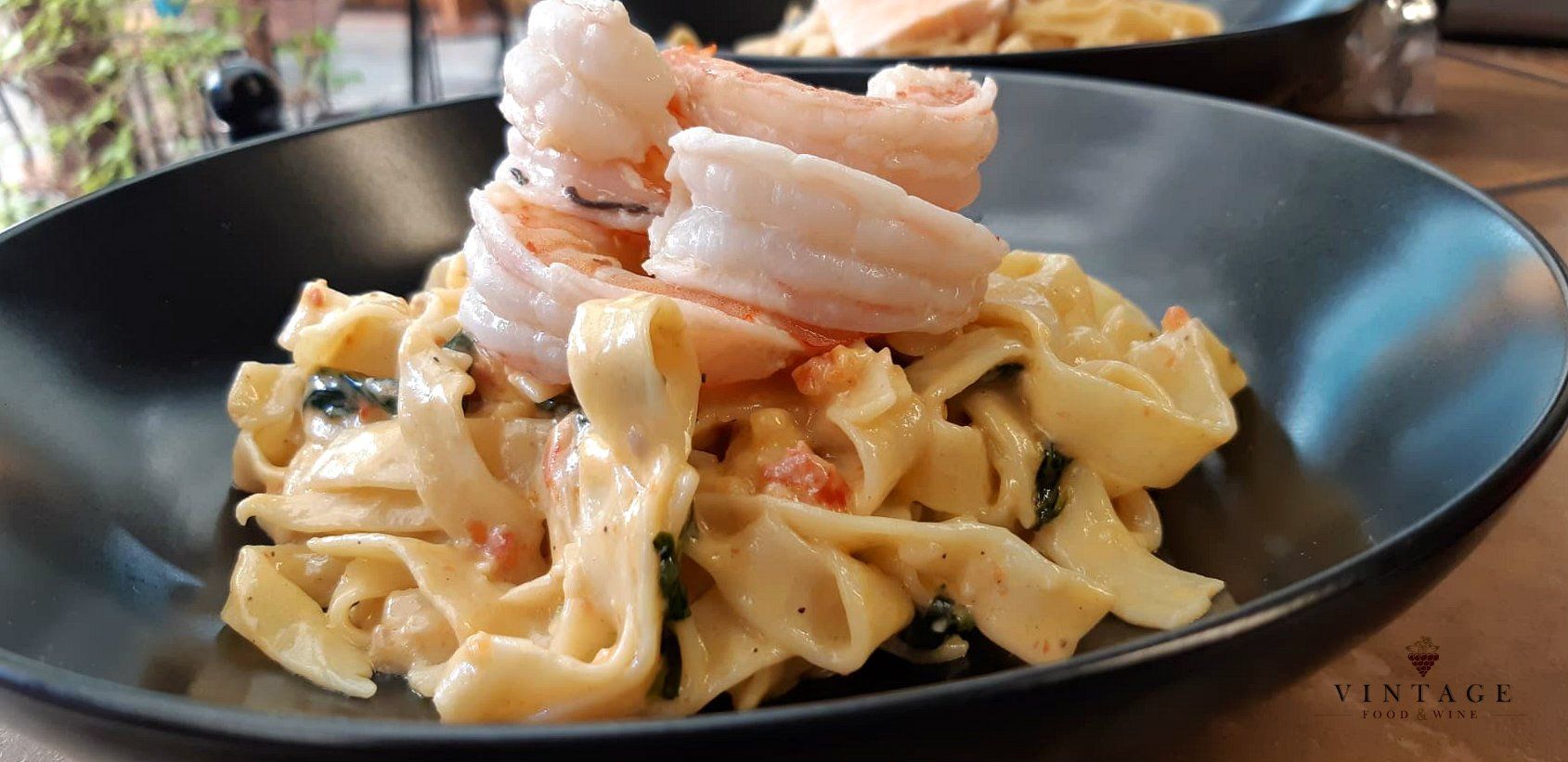 Un primer plano de un plato de pasta con camarones sobre una mesa.