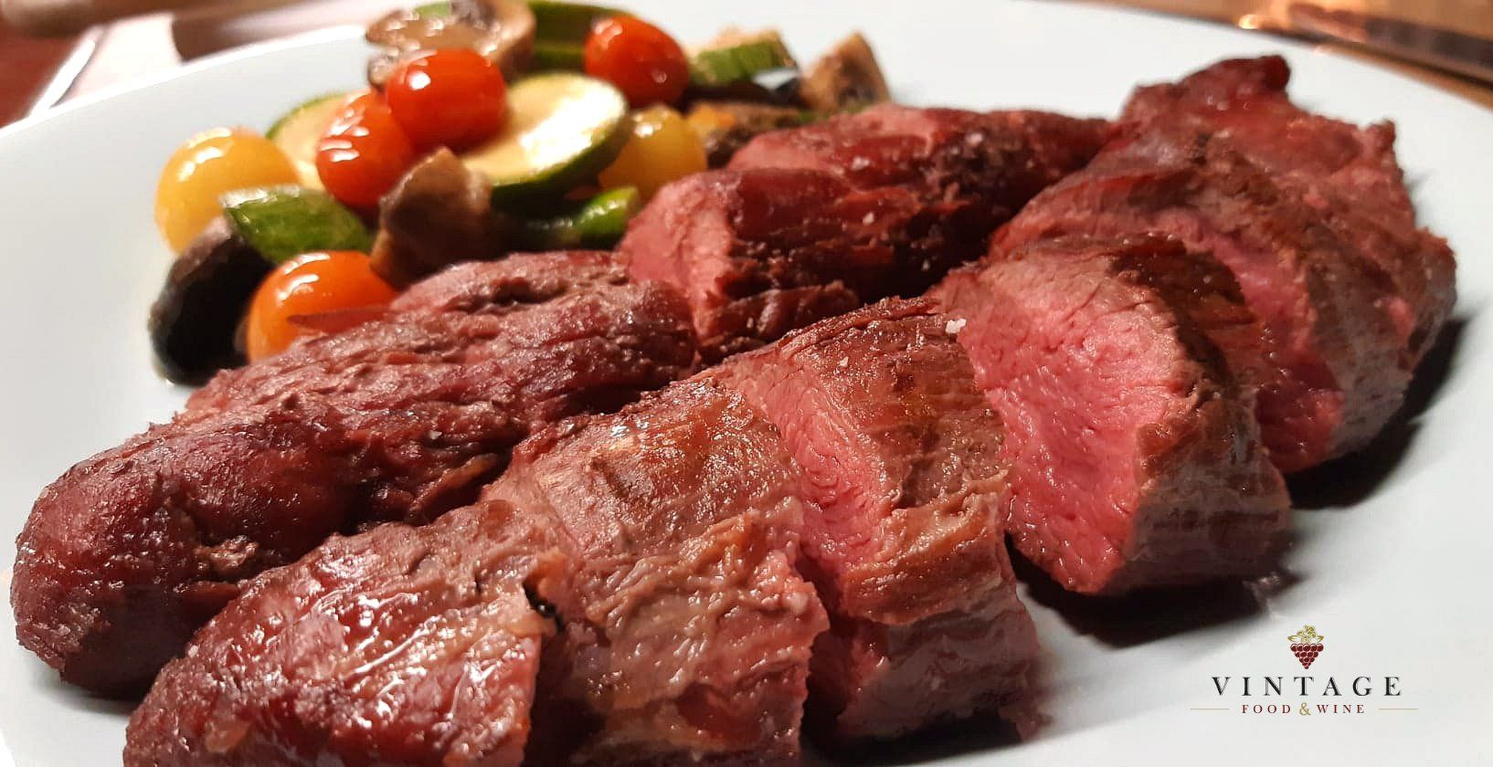 Un plato blanco cubierto con rodajas de carne y verduras.