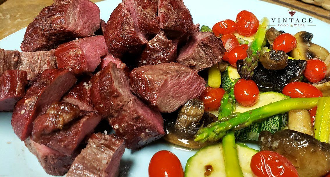 Un plato de carne y verduras sobre una mesa.
