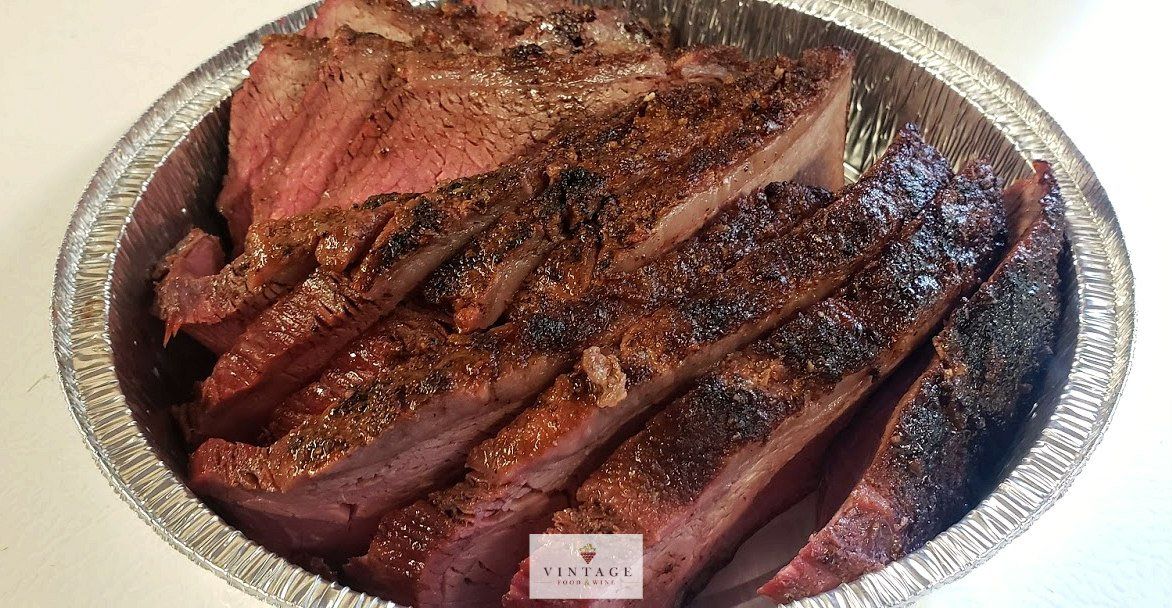 Bandeja de papel de aluminio llena de carne cortada en rodajas sobre una mesa.