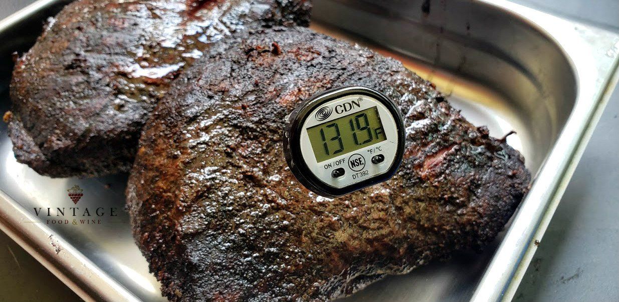 Un termómetro digital está sobre un trozo de carne en una sartén.