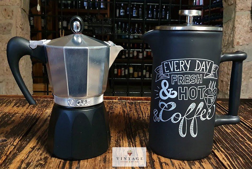 Una cafetera y una taza de café están sobre una mesa de madera.