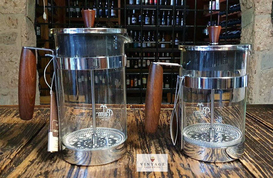 Dos cafeteras con mangos de madera están sobre una mesa de madera.