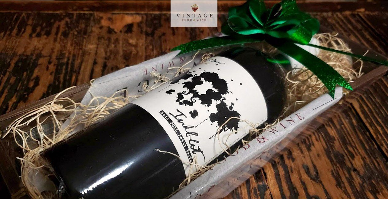 Una botella de vino está envuelta en paja y atada con un lazo verde.