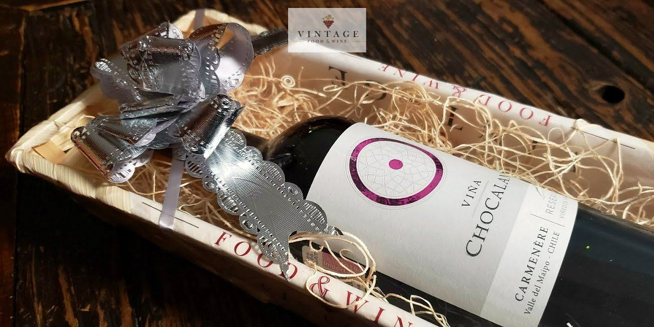 Una botella de vino está en una caja de madera sobre una mesa de madera.