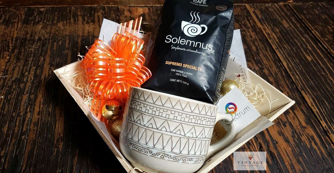 Una taza de café y una bolsa de café están en una canasta sobre una mesa de madera.