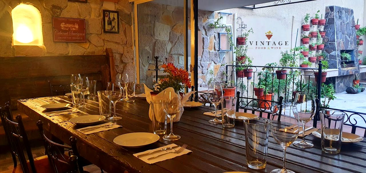 Una mesa larga de madera con platos y vasos sobre ella en un restaurante.