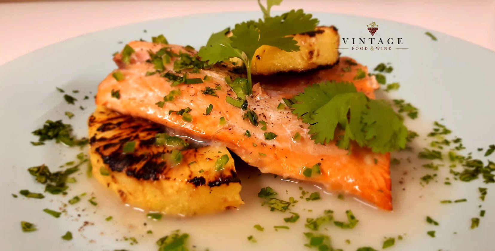 Un plato blanco cubierto con un trozo de salmón y piña.