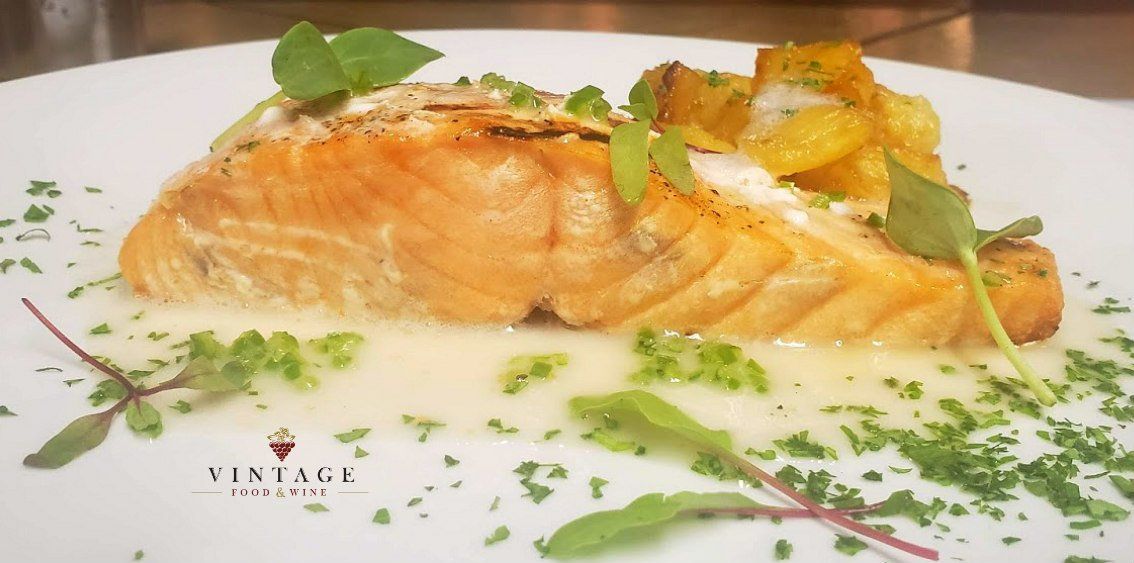 Un plato blanco cubierto con un trozo de salmón y patatas.