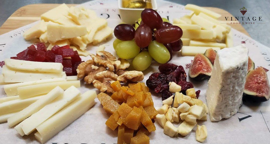 Un plato de queso, uvas, nueces e higos sobre una mesa.