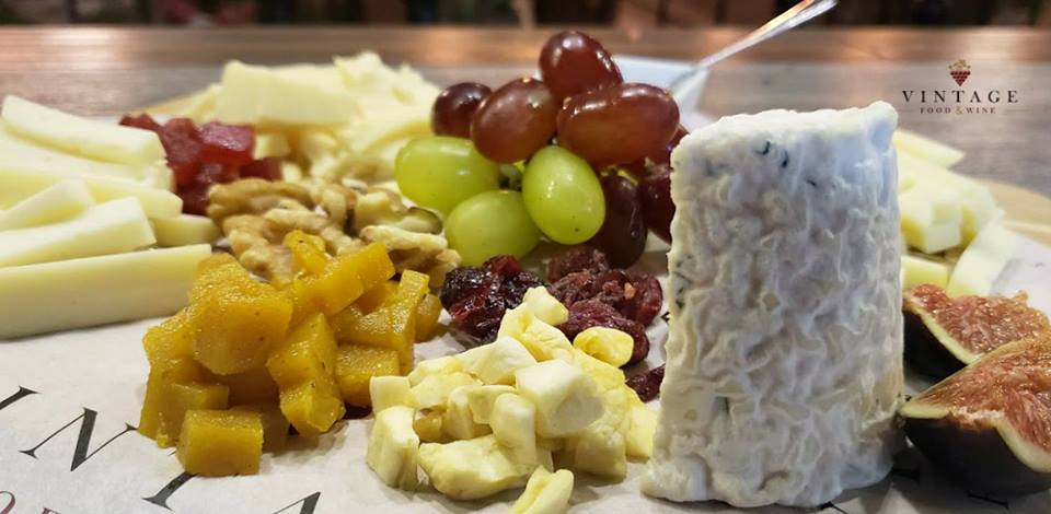 Un plato de queso, uvas, nueces e higos sobre una mesa.