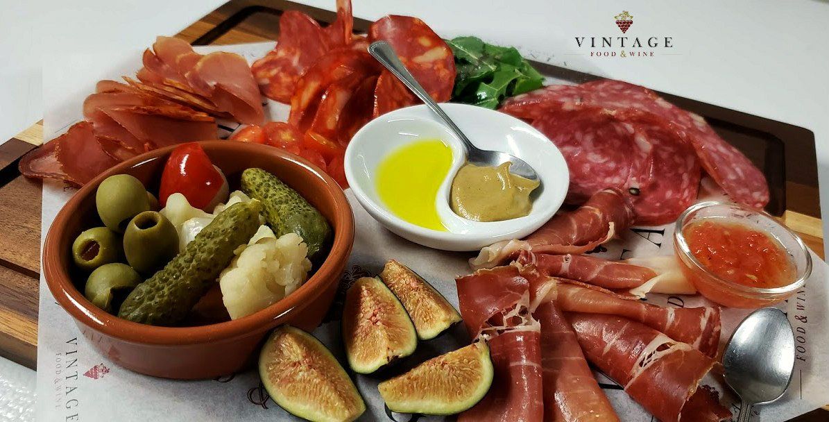 Una tabla de cortar de madera cubierta con una variedad de carnes y verduras.