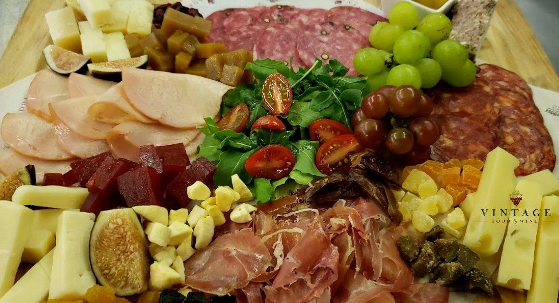 Una tabla de cortar de madera cubierta con una variedad de carnes y quesos.