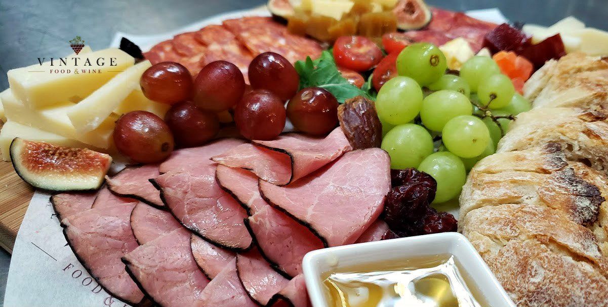 Una variedad de carnes, quesos, uvas y pan en una mesa.