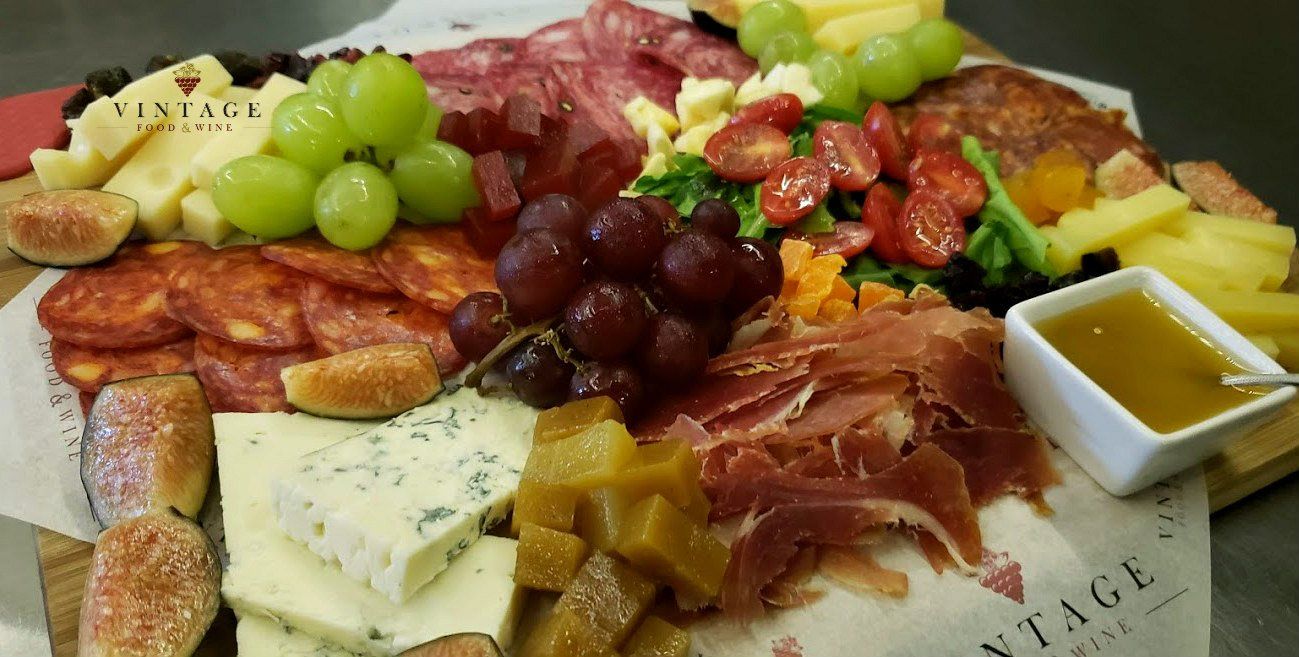 Una variedad de carnes, quesos, frutas y verduras en una tabla de cortar.