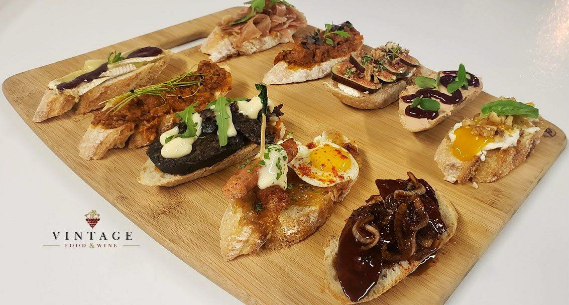 Una tabla de cortar de madera cubierta con una variedad de sándwiches.