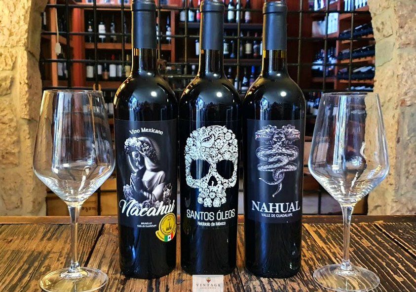 Tres botellas de vino con calaveras y serpientes en ellas.