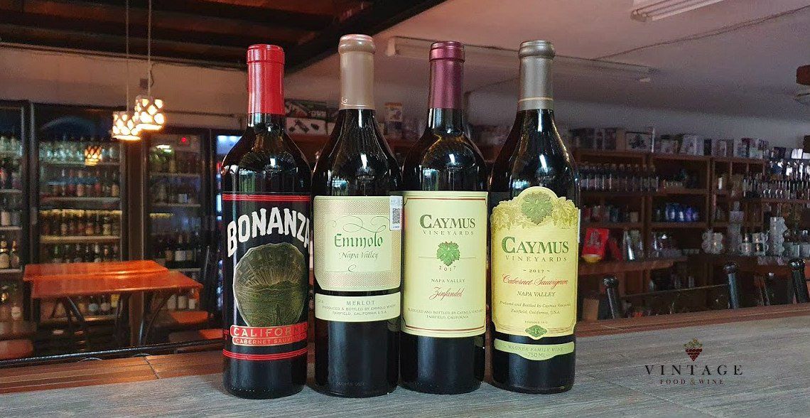 Cuatro botellas de vino están alineadas en una barra.