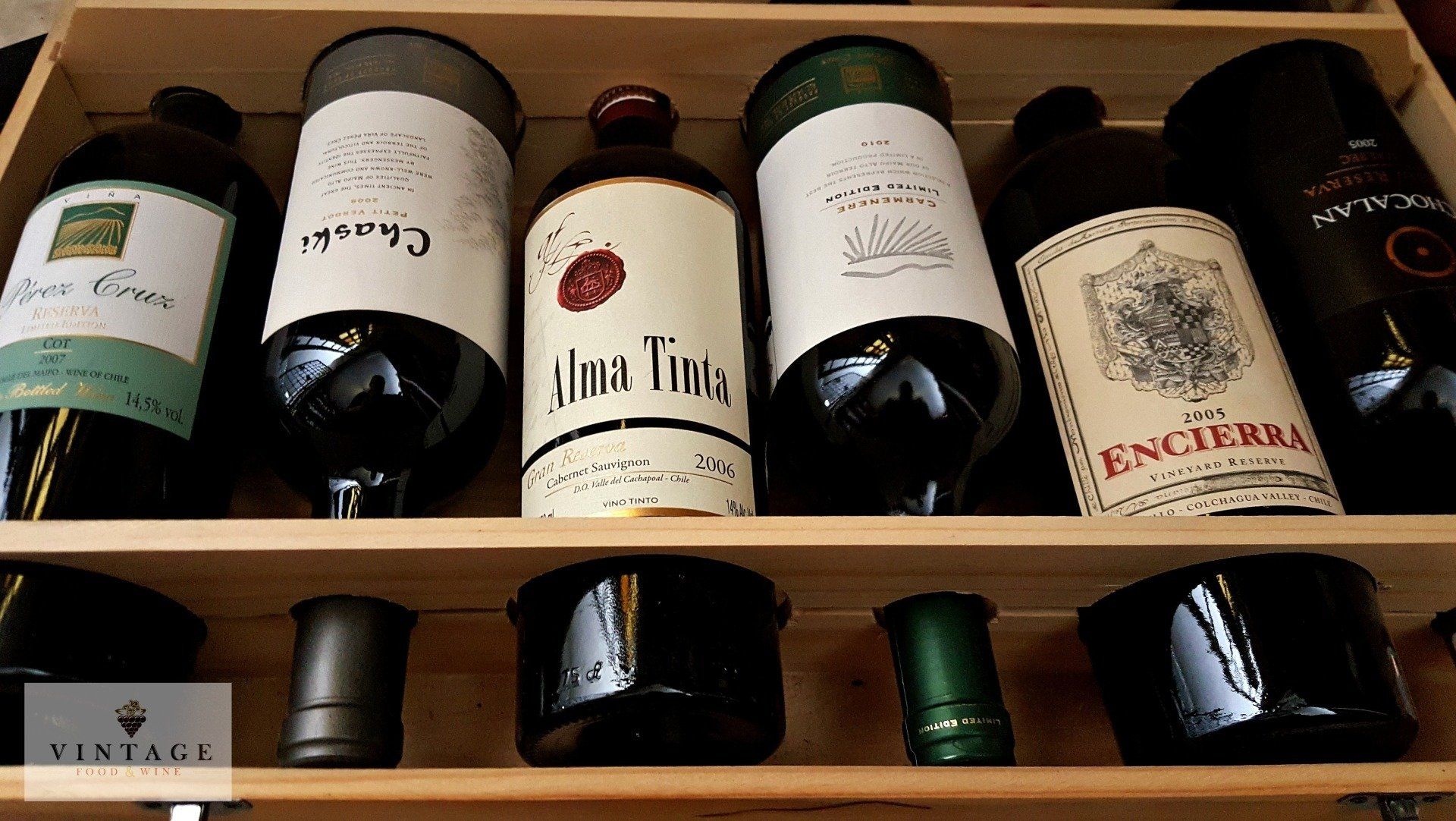 Varias botellas de vino están alineadas en una caja de madera.