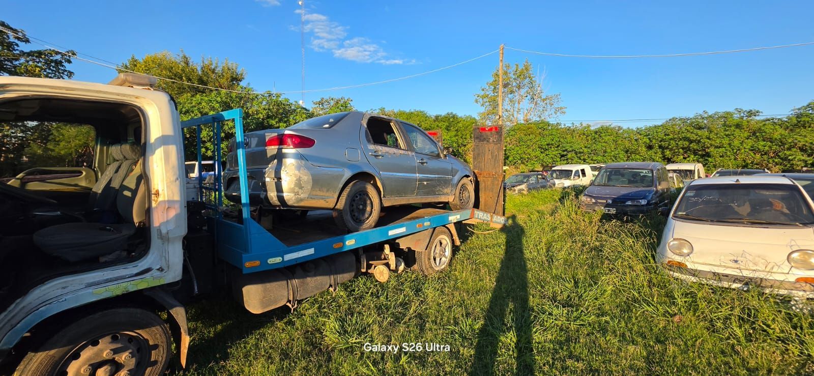 Un camión transportador de automóviles lleva un coche plateado en un soleado 