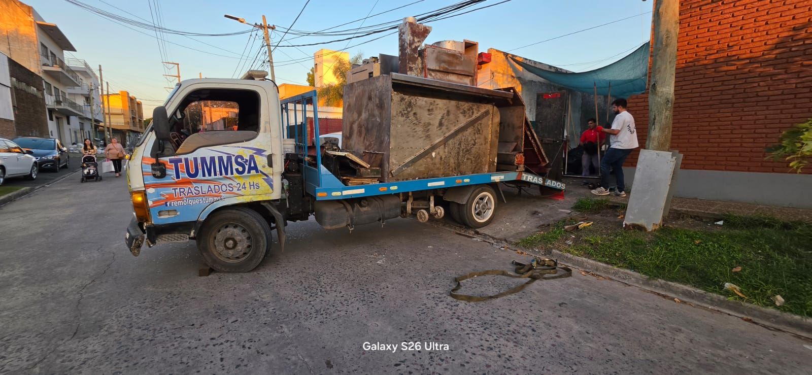 Un pequeño camión azul transporta una gran estructura de madera