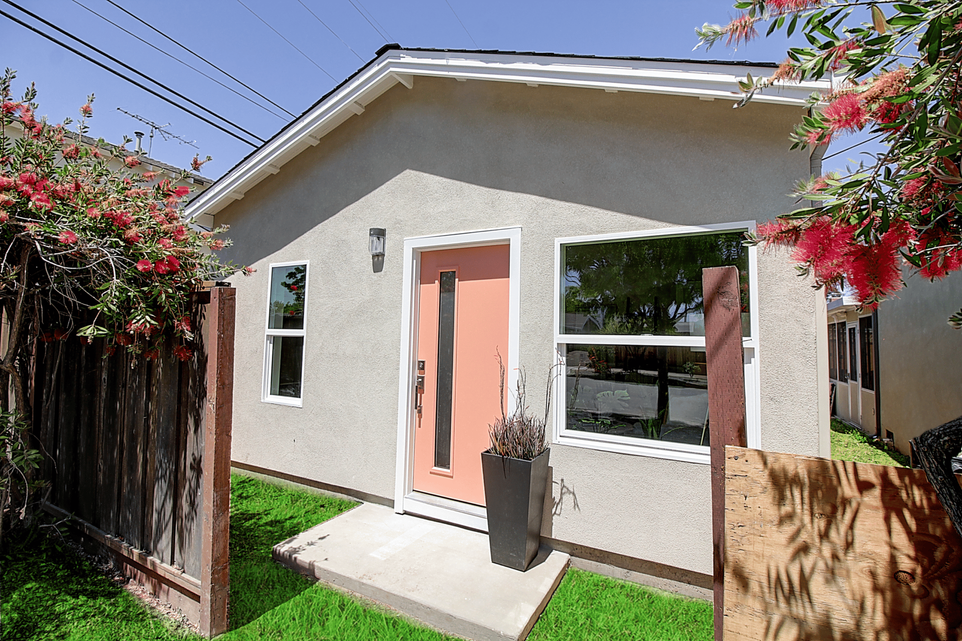 A small house with a fence and flowers in front of it